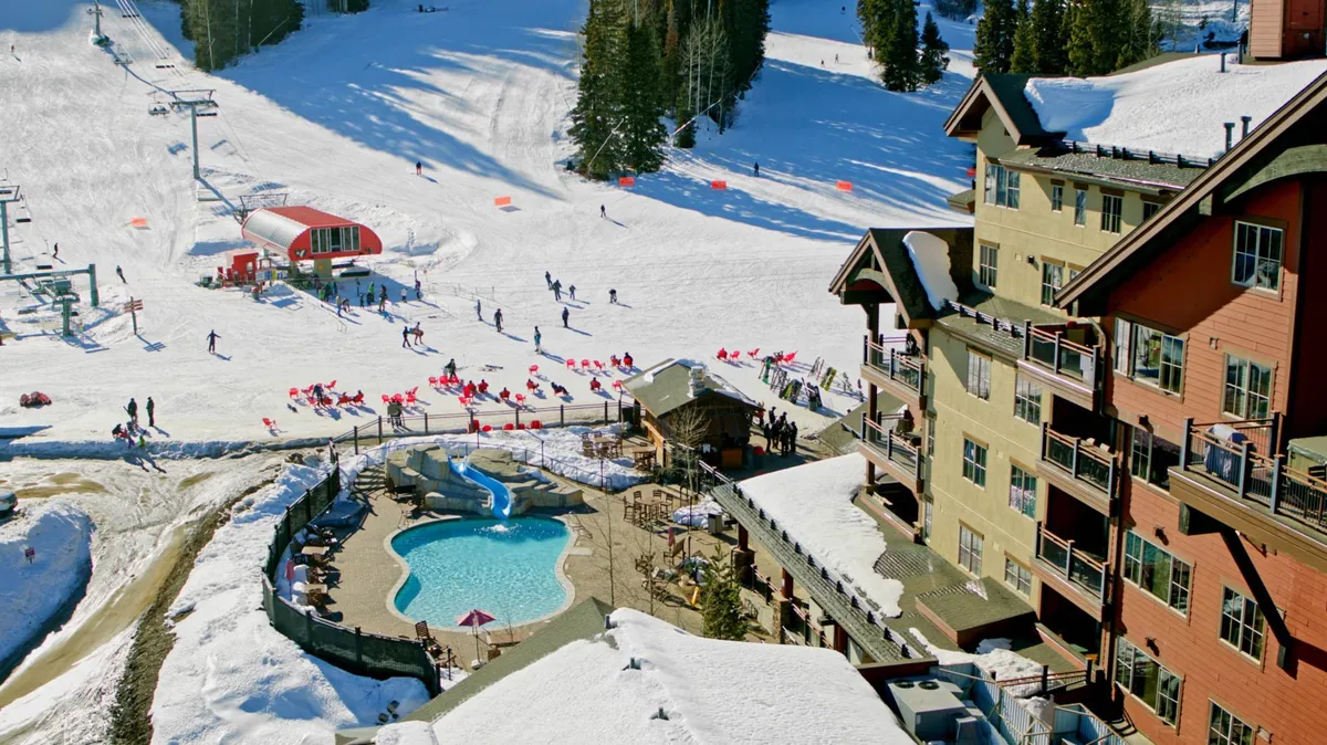 A dynamic exterior scene featuring ski slopes, a ski lift, and an inviting heated outdoor pool adjacent to the lodge. The snow-covered landscape buzzes with skiers, and the pool area offers a relaxing counterpart to the action, hinting at ways to unwind after a day on the mountain.