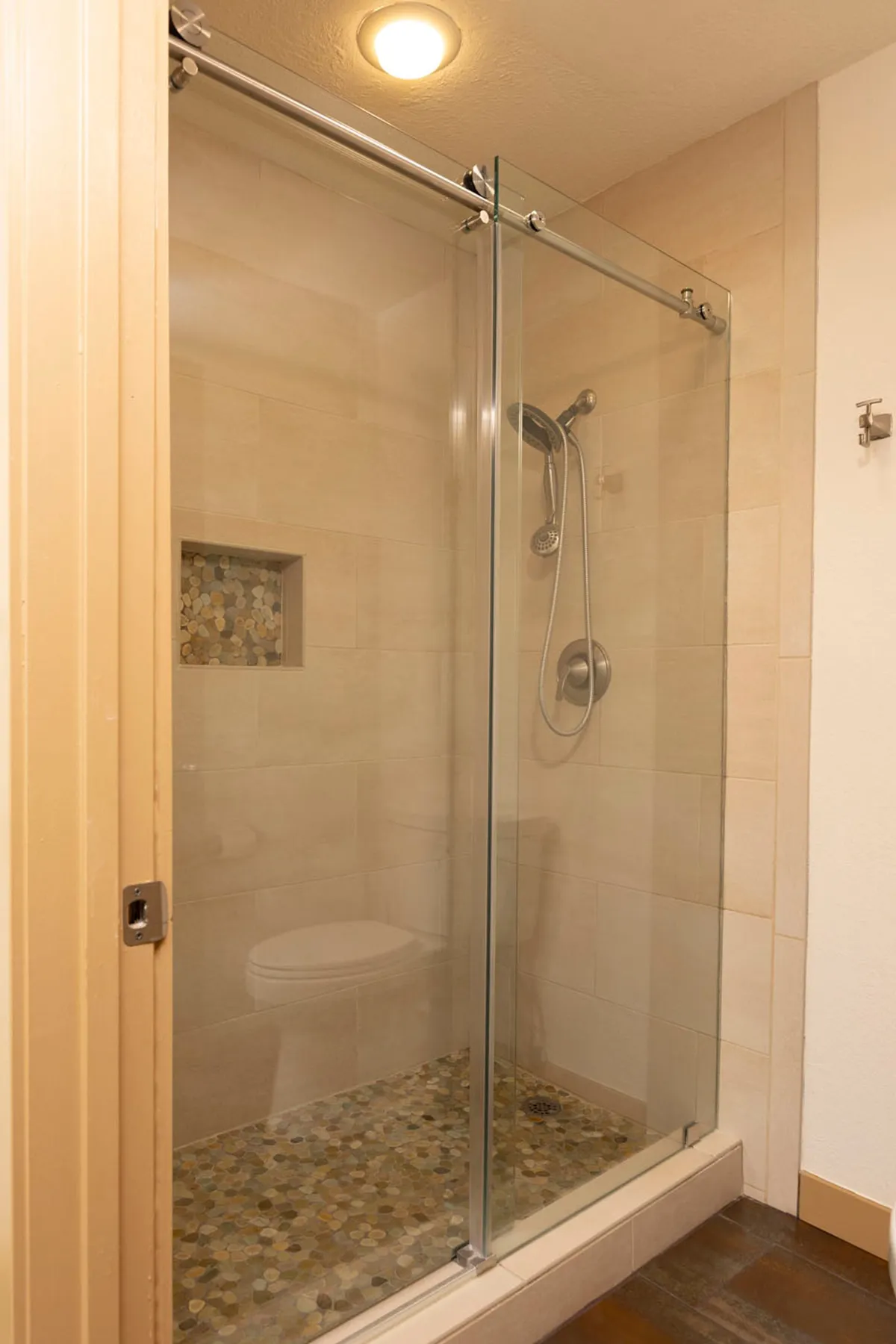 A spa-inspired bathroom featuring a sleek glass shower enclosure, textured stone wall, and modern fixtures. The tranquil setting exudes relaxation and rejuvenation, ideal for unwinding after a day on the slopes or exploring the resort.