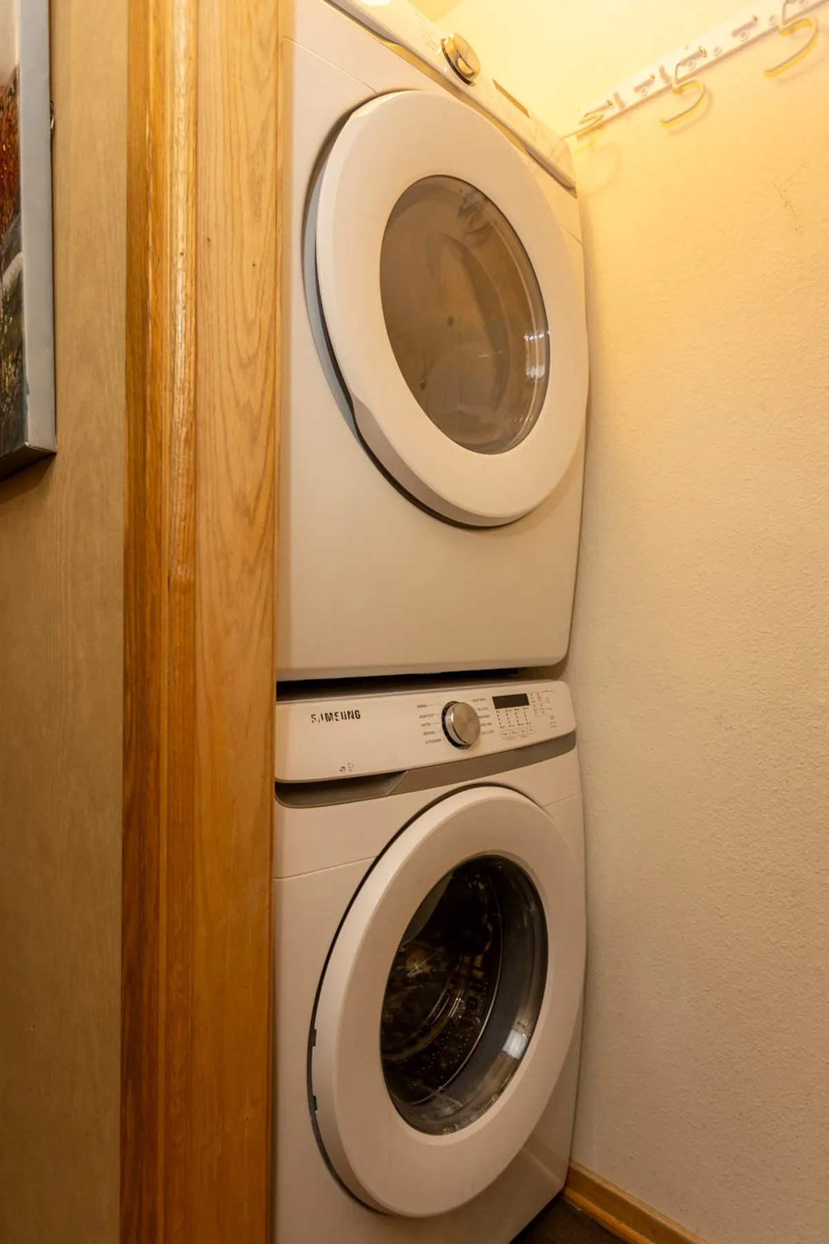 This image highlights the dedicated laundry area, featuring a stacked washer and dryer set against wooden cabinetry and equipped with wall hooks for organization. The scene is clean and practical, underscoring the convenience of on-site laundry for extended stays or active getaways.